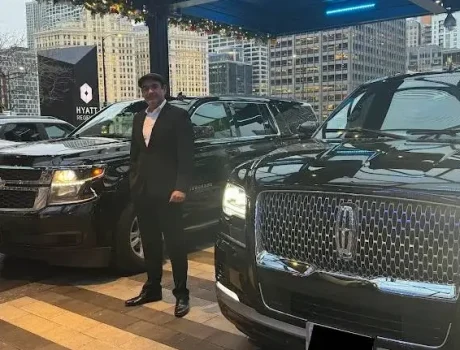 Driver Stands in front of a black Lincoln Navigator