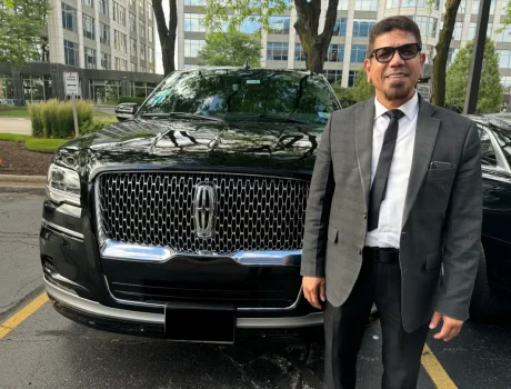 Driver Stands in front of a black Lincoln Navigator
